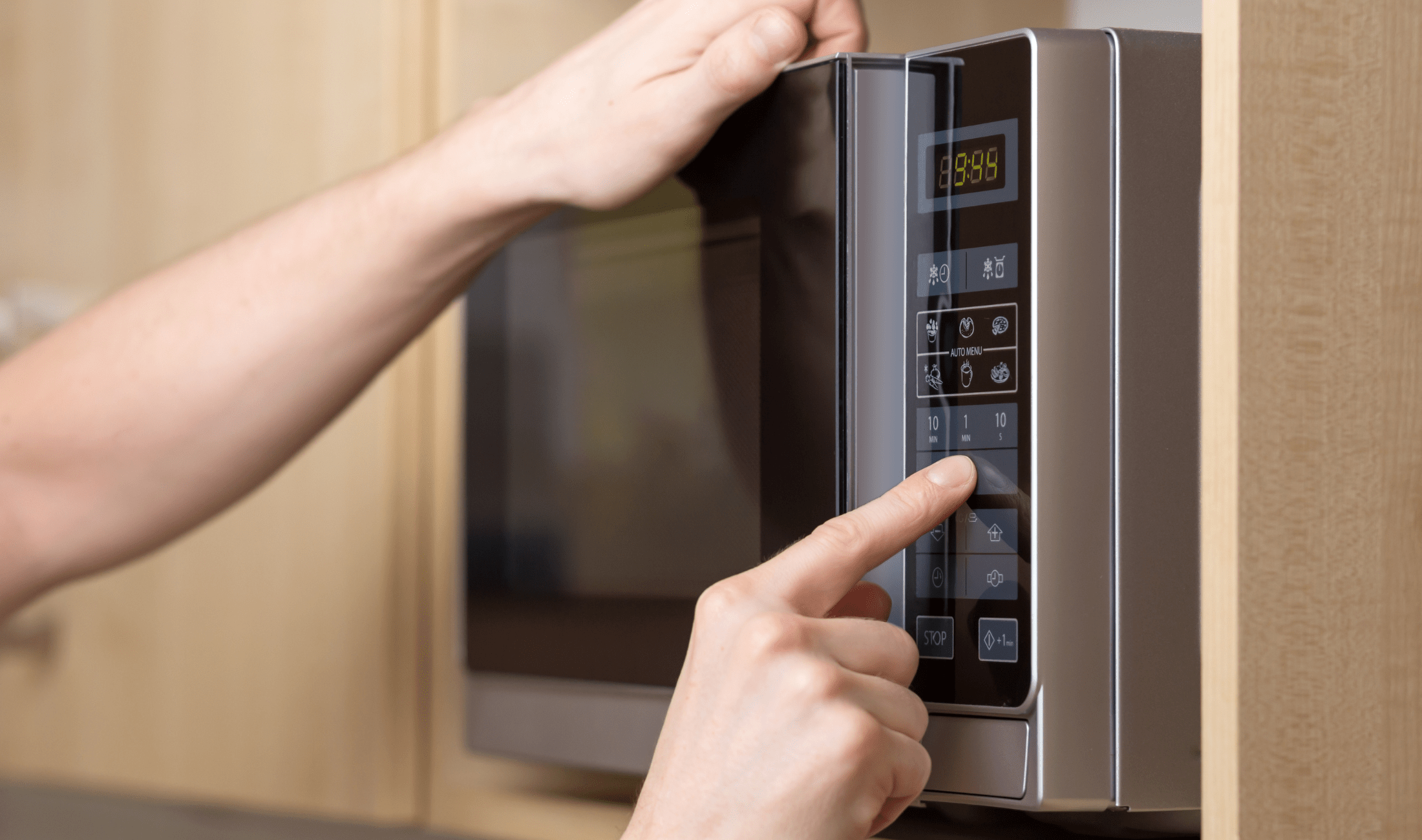 A  person pushing buttons on a microwave.