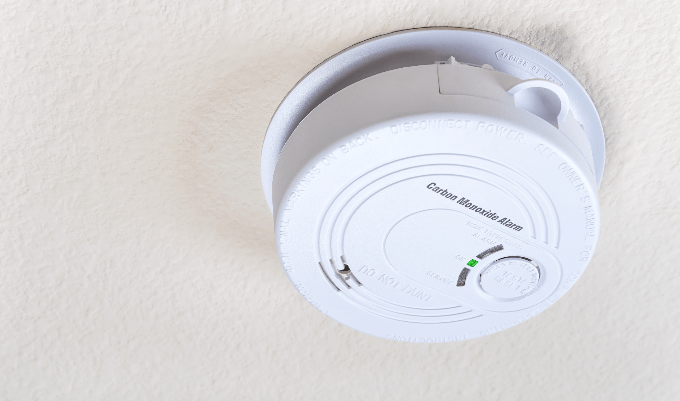 A carbon monoxide detector on a ceiling.
